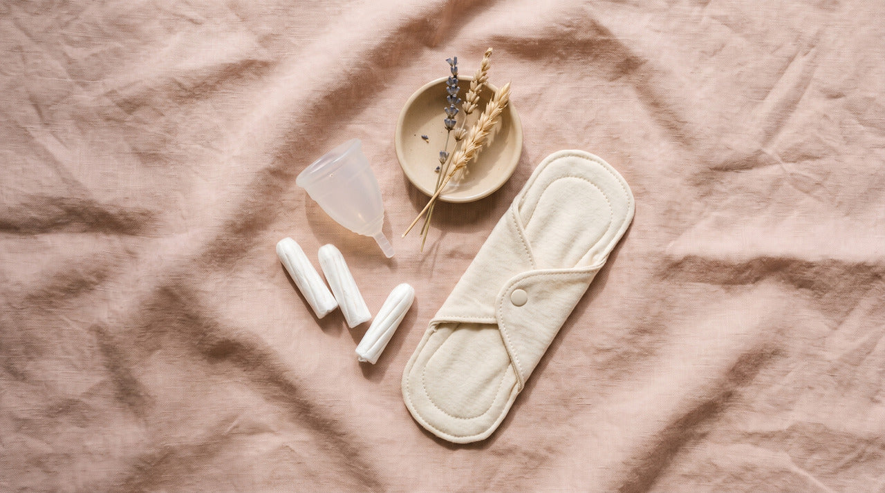 Menstrual cup, tampons and a reusable cloth pad on pink linen